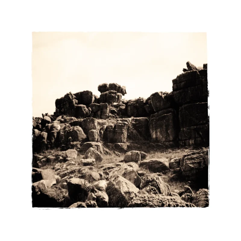 A photograph taken in sepia of interesting rock formations and the stones in front of it.